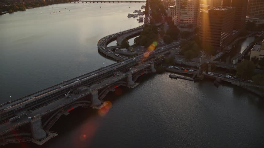 Setting sun shines across traffic on highways and bridge in city downtown