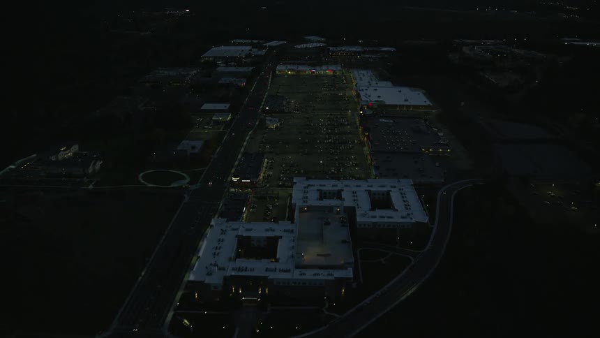 A dark city is shown via aerial view with driving cars and buildings