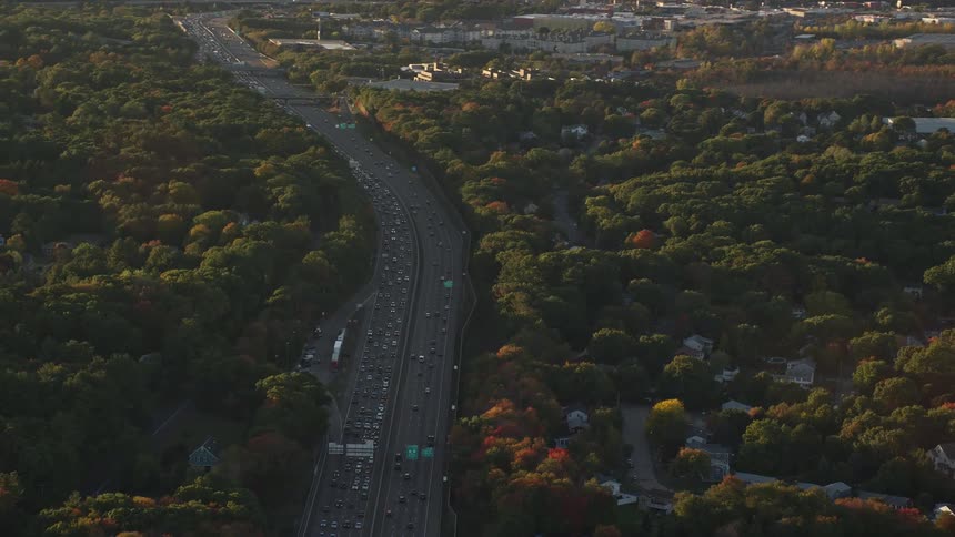 Aerial panorama of a residential neighborhood amidst green areas and next to a highway