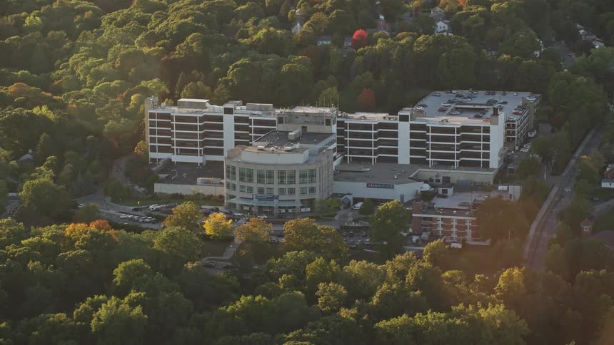 Aerial panorama of a building amidst green areas with sunlight reflection