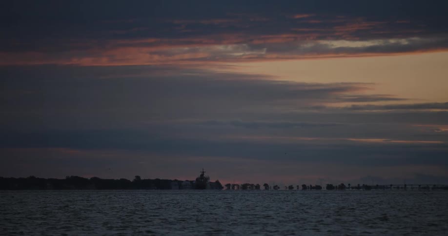 A vast ocean sits beneath a blue and orange sky