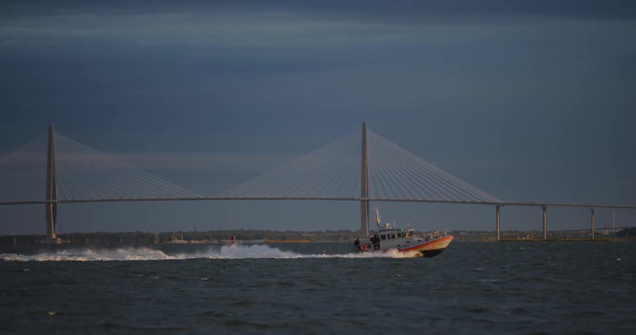A vessel sailing at sea with a bridge in the background
