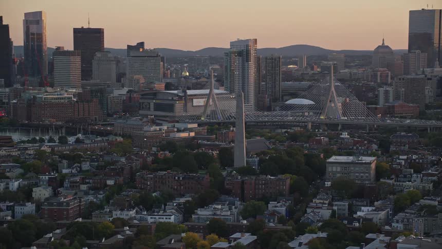 From an aerial perspective the city at dusk is immersed in a golden hue with the silhouettes of skyscrapers standing starkly against the diminishing sky