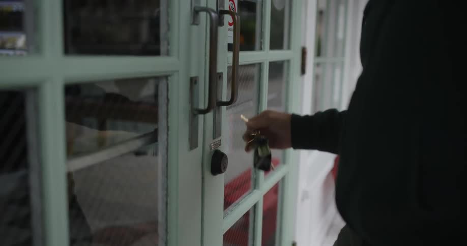 A person in a coat opening a door with a key