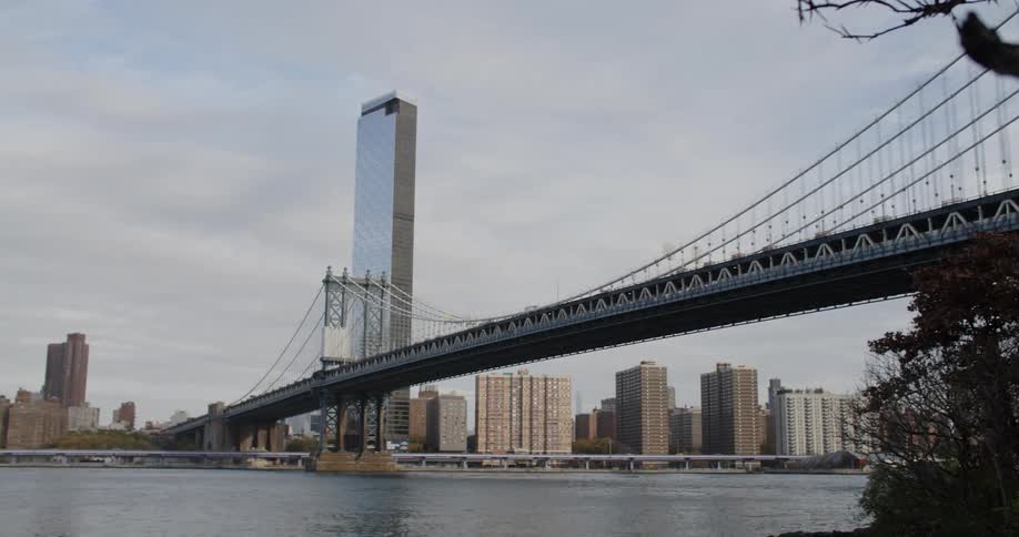 A large bridge that passes over a river and connects with a city with tall buildings