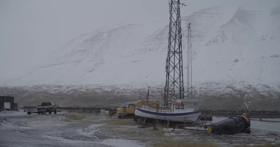 View of snowcovered mountains with a passing vehicle and a docked boat