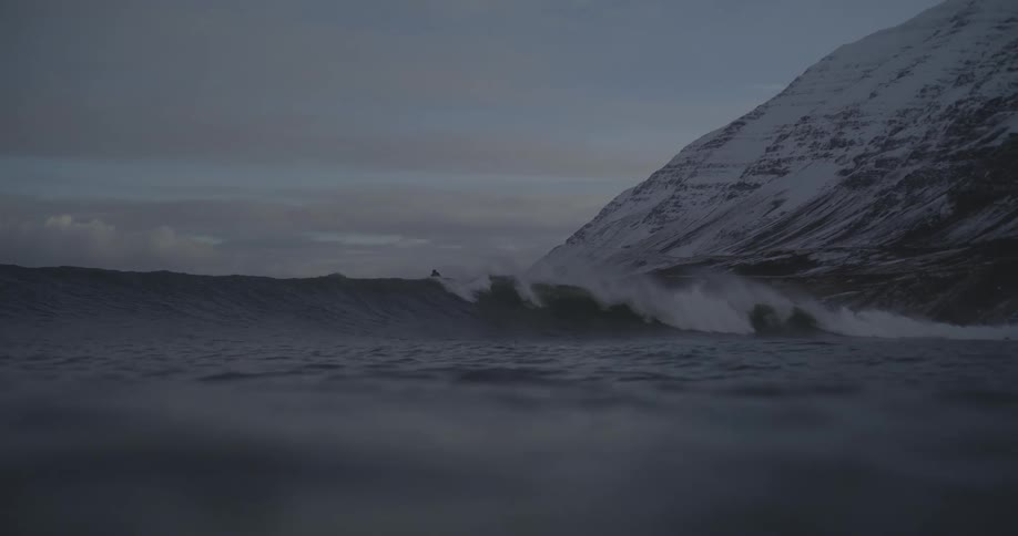 A person surfing a wave at dusk