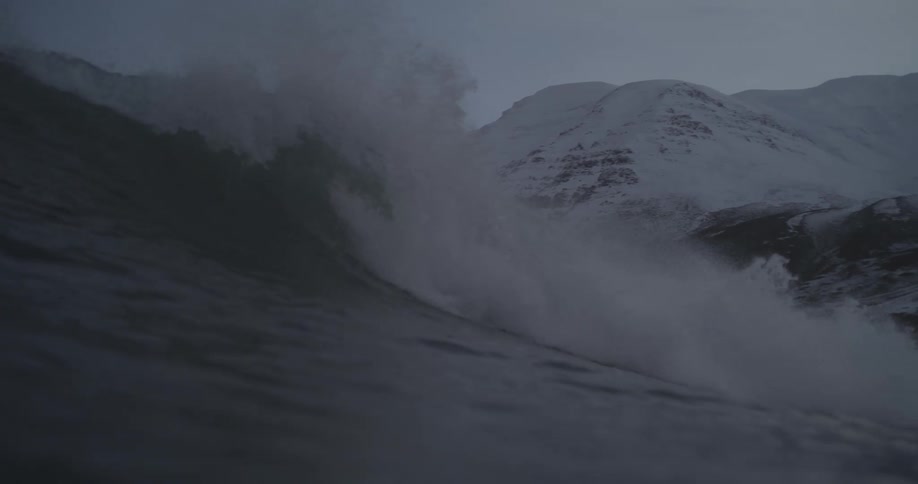 Ocean waves next to the snow covered mountains