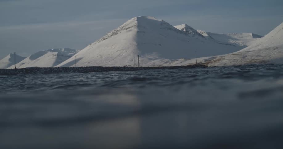The mountains on the shore are covered in snow