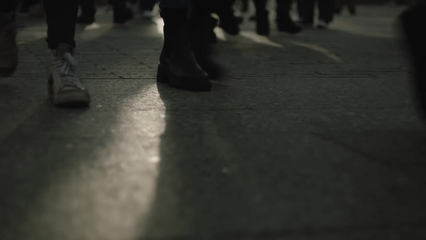 Closeup of peoples feet walking on a concrete sidewalk