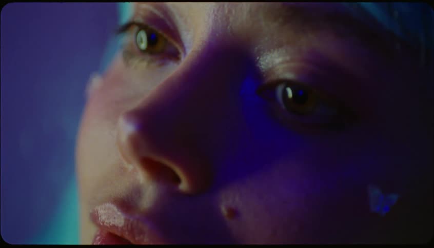 Young woman gluing a small shiny butterflyshaped gem on her face