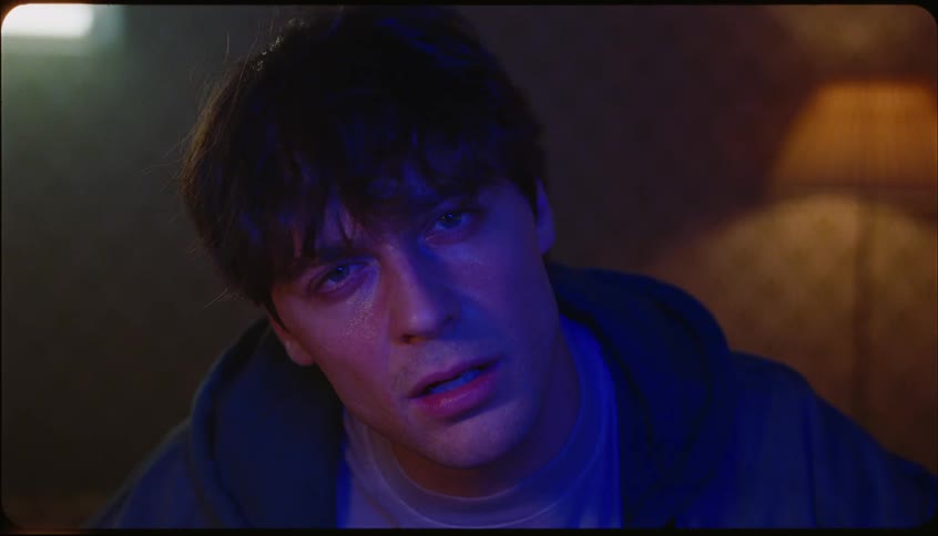 Portrait of a young man staring directly into the camera with lights on his face