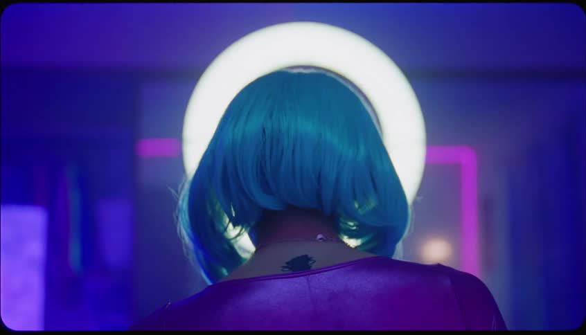 Woman facing a led ring light gesturing with her hands with her back to the camera