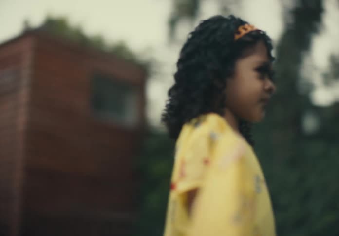 Young girl walking in the backyard wearing a yellow dress