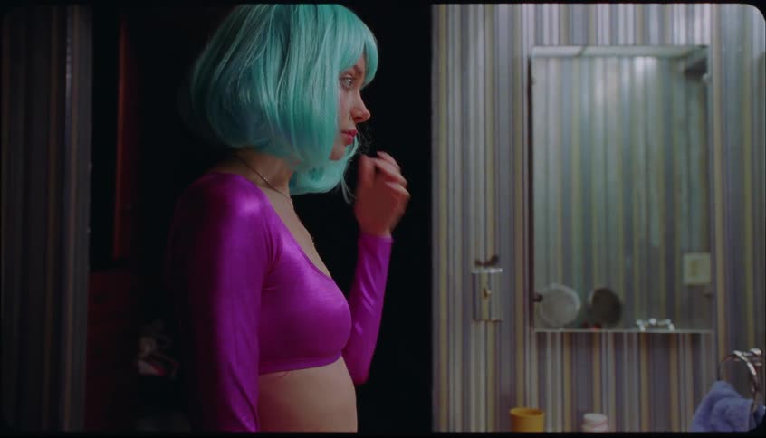 A woman removes her wig in the bathroom