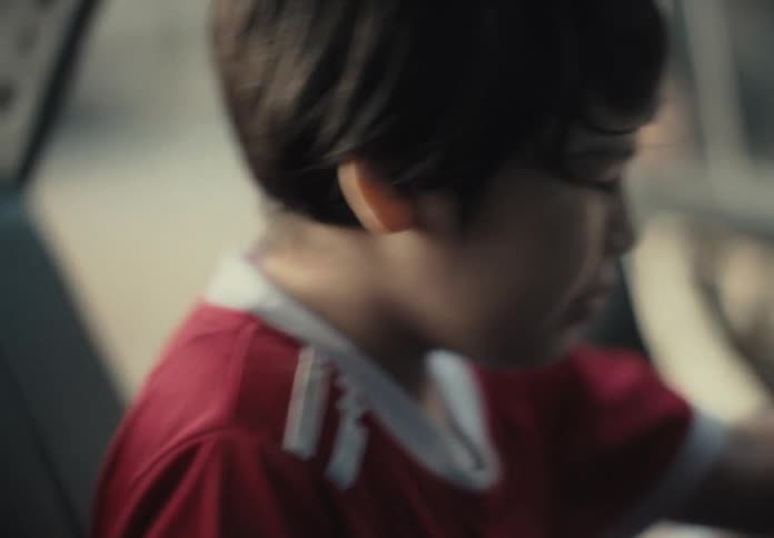 A boy walks to a car and when he gets in he starts crying