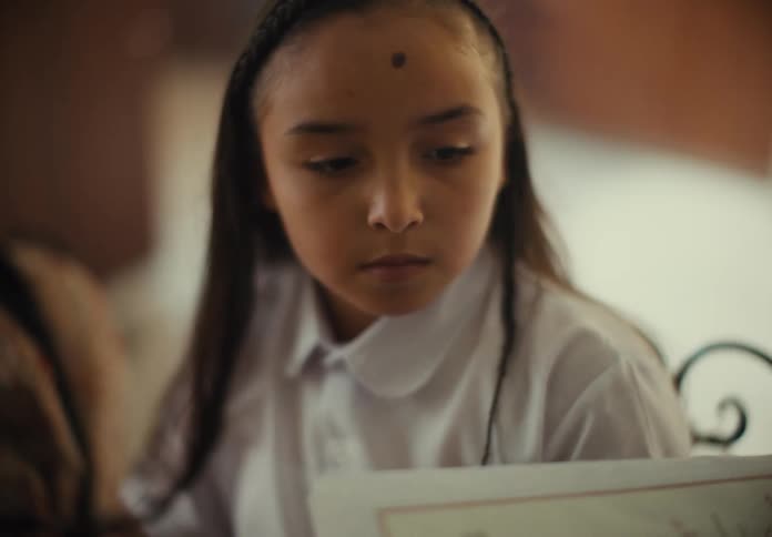 Portrait of a girl handing her notebook to someone with an apprehensive expression