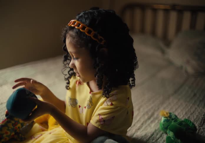Little girl sitting on the bed playing with some toys and looking happy