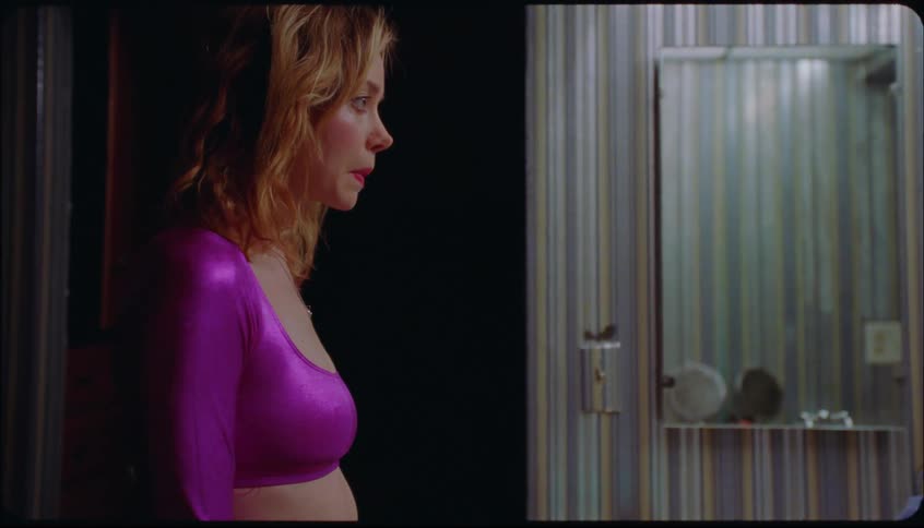 Woman in a pink dress looking at herself in the bathroom mirror