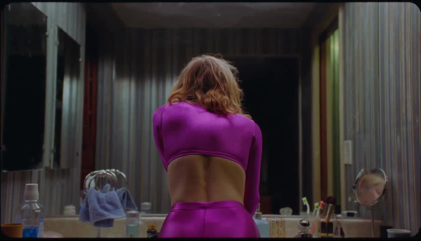 A woman removes her wig in the bathroom