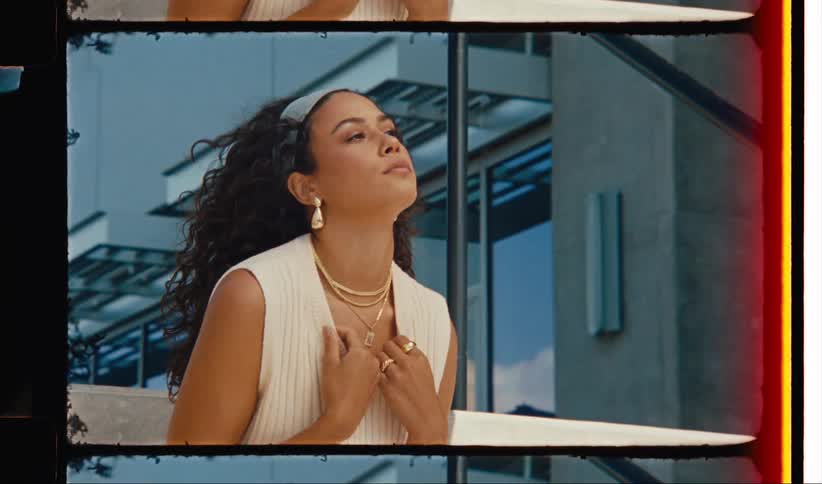 Female model wears fashionable attire while standing near buildings reflective window