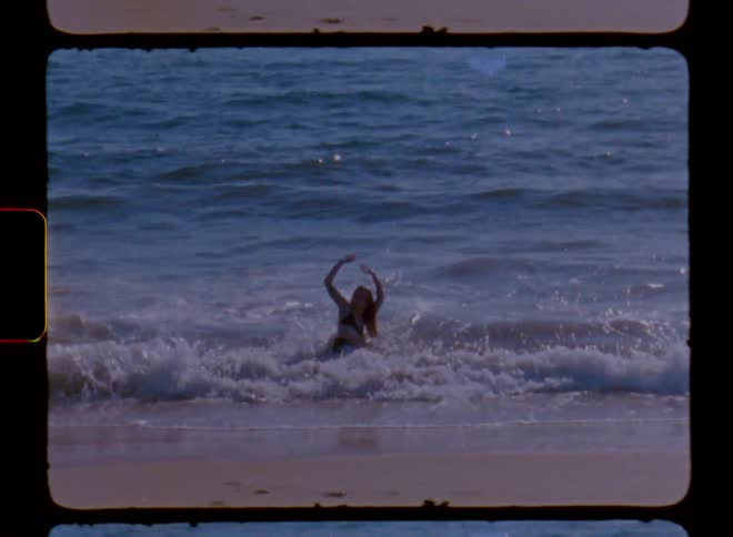 Female dancer dances in the surf on bright sunny day