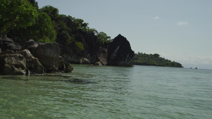 The shore is surrounded by rocks and hills covered with trees