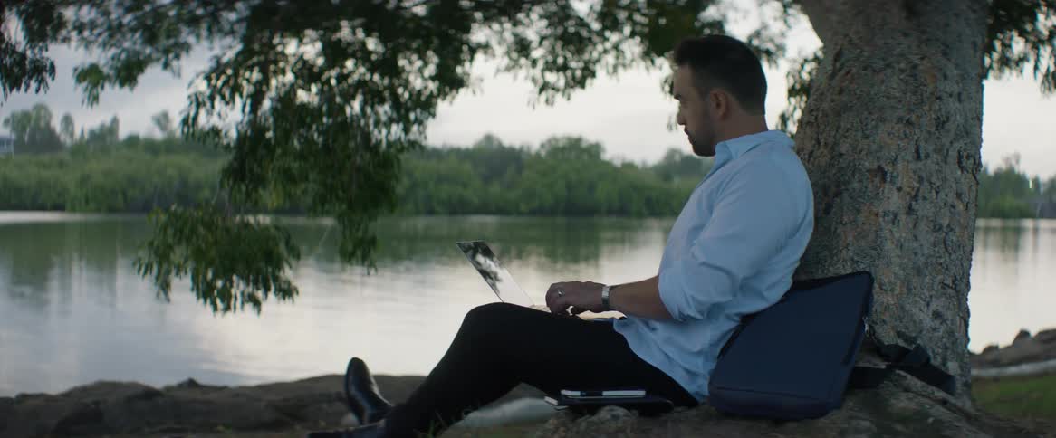 A man sitting on the grass with a laptop computer on his lap