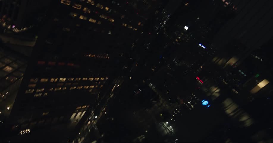 The top to the bottom of a reflective commercial building in a metropolitan city at night