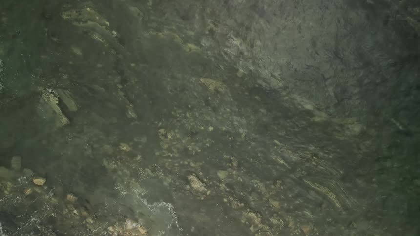 Aerial of rocks and water waves at midday