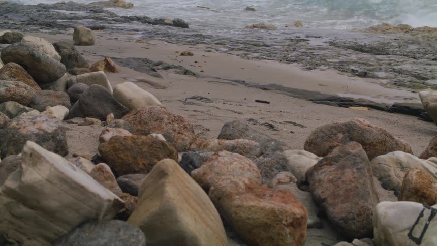 Beachside with rocks and sea waves breaking on the sand