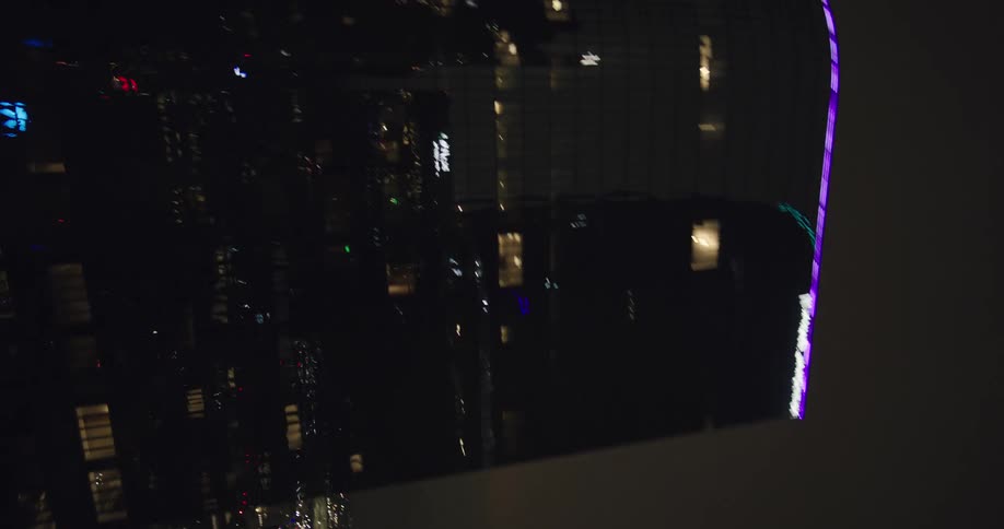 Disorienting drone shot of tall skyscrapers in the city at night