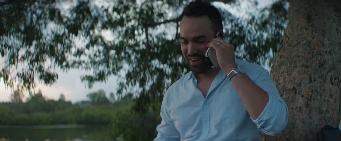 A man sitting in a tree talking on his cell phone