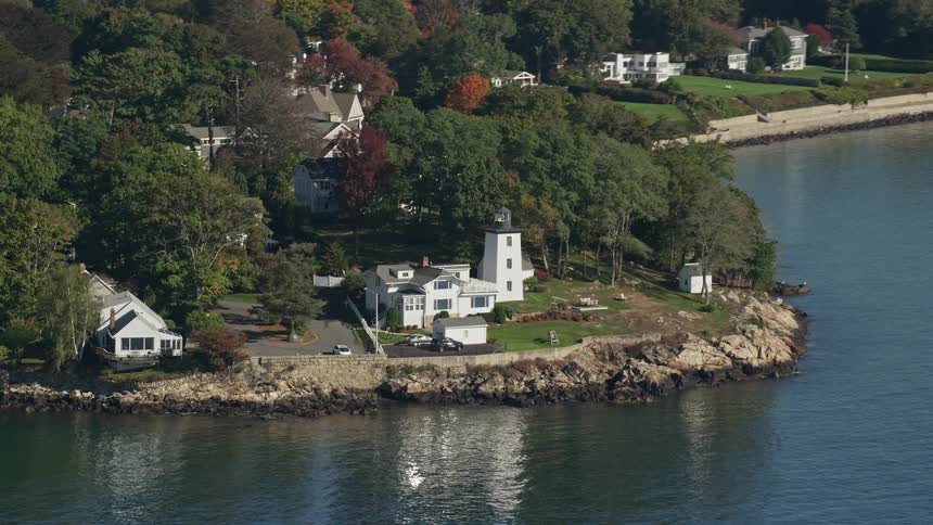 A large white house facing a lake on a rocky shore
