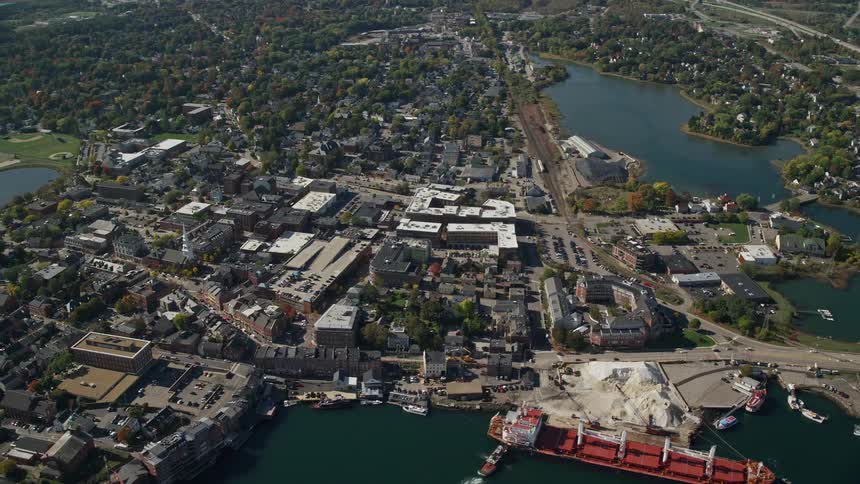 Aerial of an urban coastal city with a ship docked at a marina
