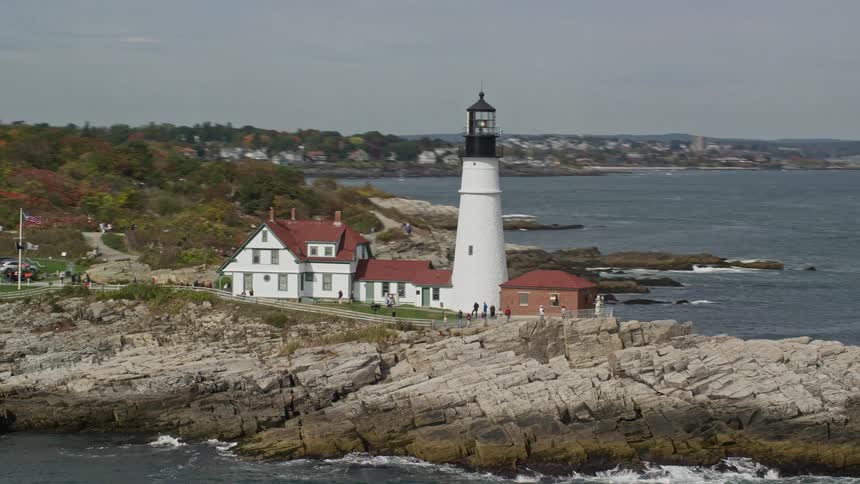 A white lighthouse on top of some rocks on an ocean coast