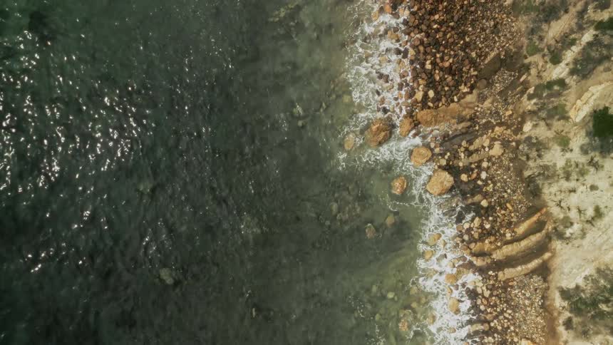 A sea coast with some waves breaking on the rocks on the beach
