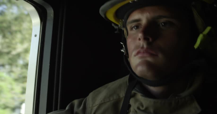 A fireman rides in a firetruck to the scene of a fire