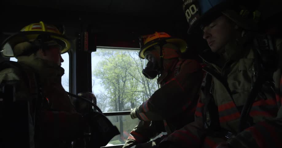 Firefighters are traveling in a truck before storming out as it stops