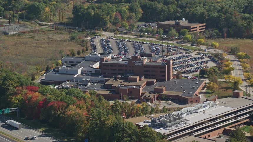 A huge shopping mall building with a large parking lot full of cars behind it