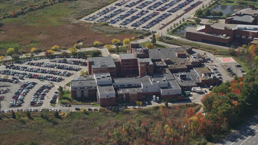 An aerial view of a cluster of buildings with a huge car park next to it