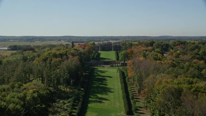 An aerial view in the daytime of a countryside manor near the coast