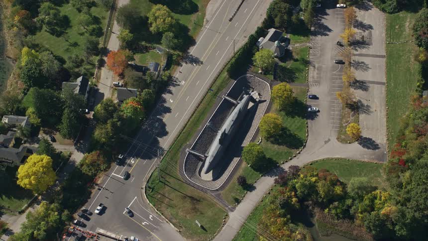 Finned rocket sits on road median between waterfront and intersection in residential neighborhood
