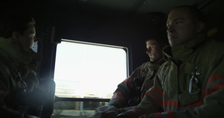 Firemen gear up while traveling in a firetruck