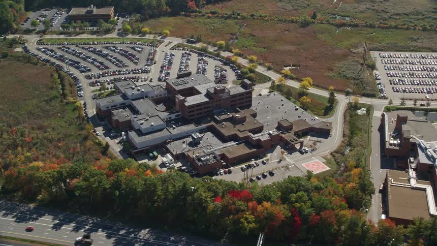 A large commercial building with a huge parking lot full of cars next to it