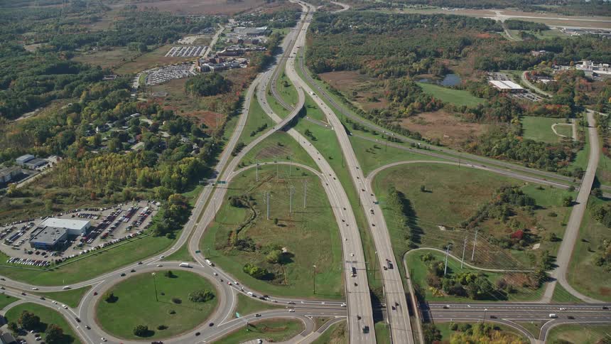 An aerial panorama of an urban city next to a highway with green areas