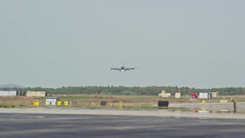 An airplane flies low near the airport and comes in for a landing on the tarmac
