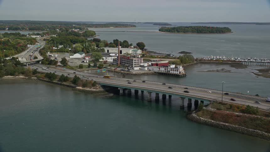 An aerial panorama of a seaside bridge with vehicles passing