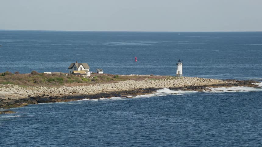 A lighthouse in front of a large wooden house on the beach