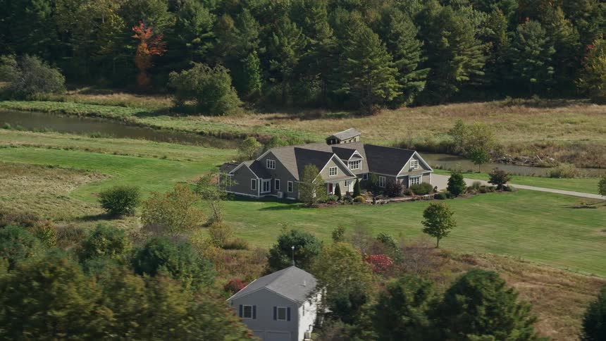 Aerial view of a house near a river and an autumn forest